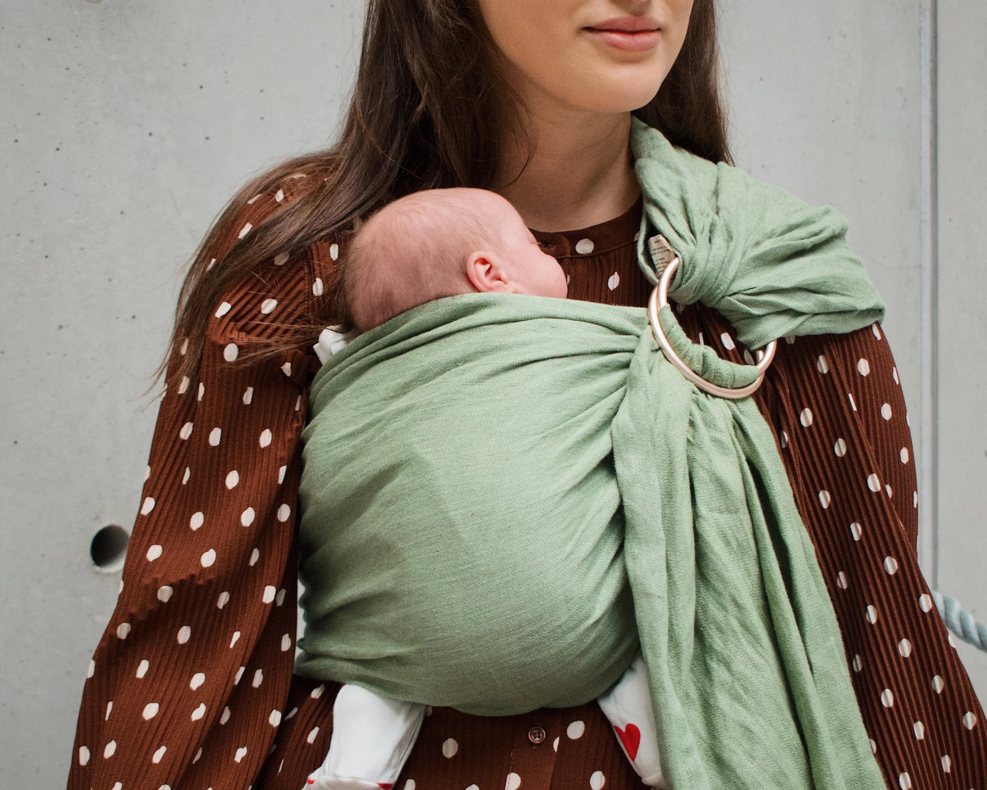 Maman portant son bébé en sling après une césarienne, sans pression sur la cicatrice.