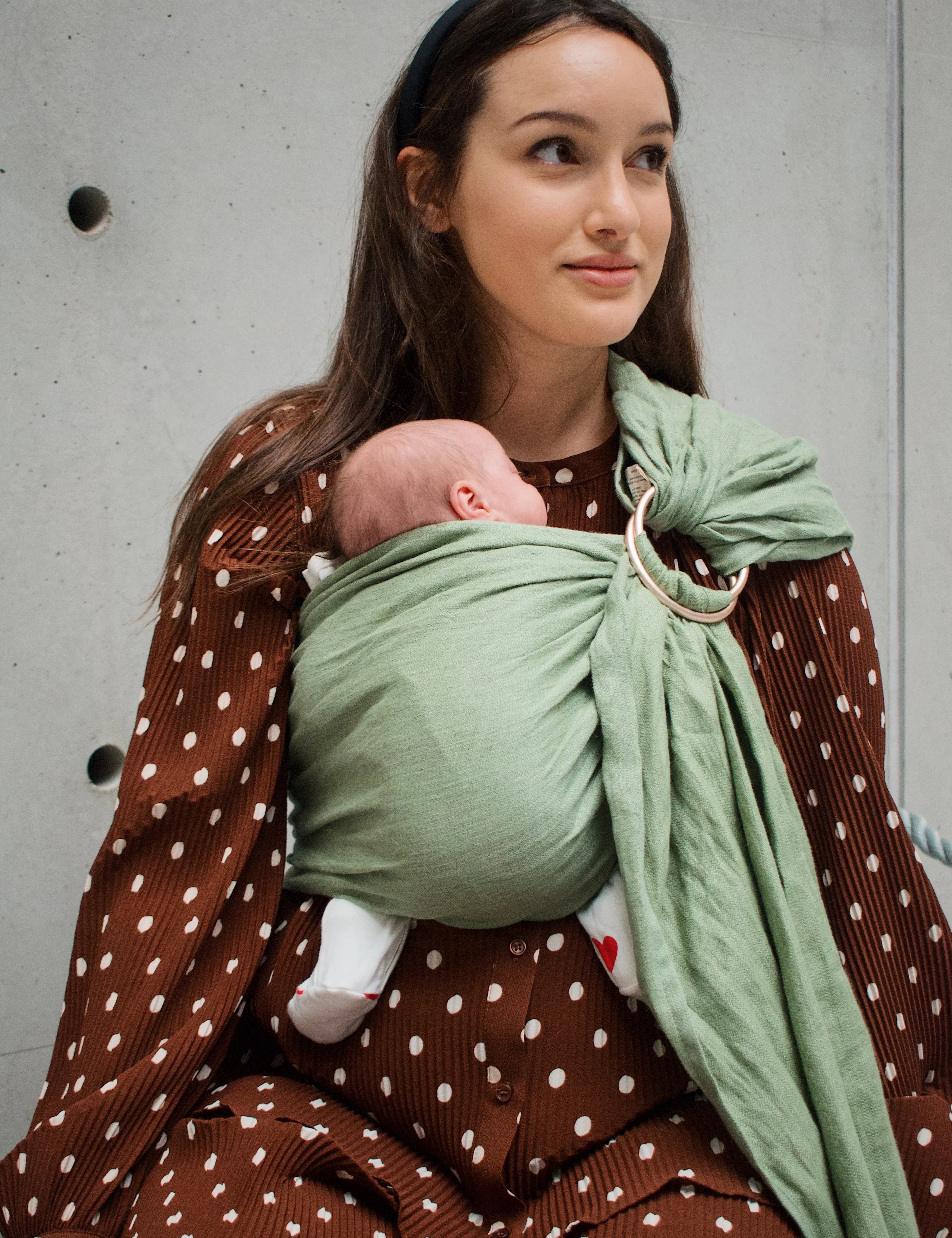Maman portant son bébé en sling après une césarienne, sans pression sur la cicatrice.