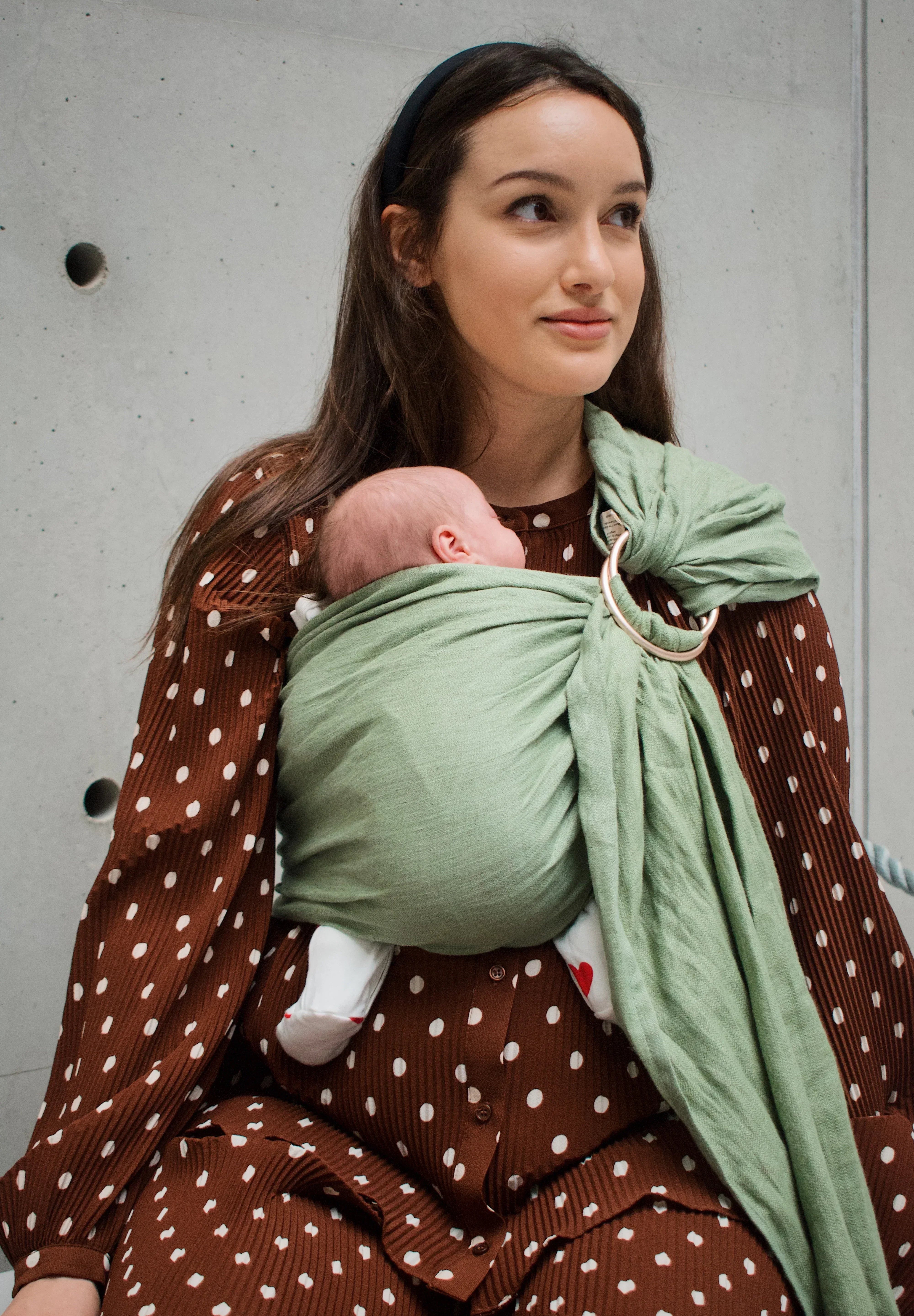 Maman portant son bébé en sling après une césarienne, sans pression sur la cicatrice.