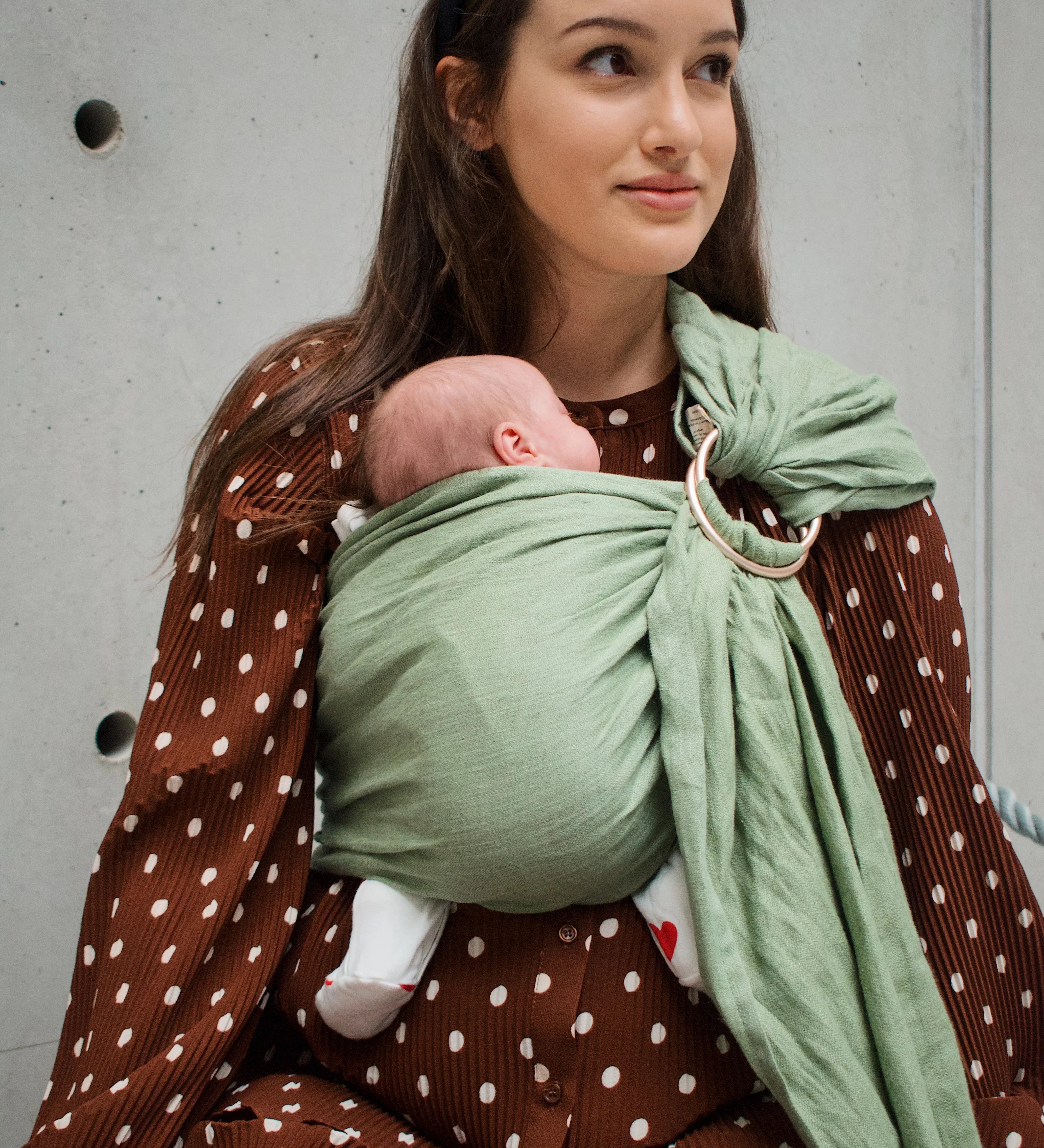 Maman portant son bébé en sling après une césarienne, sans pression sur la cicatrice.