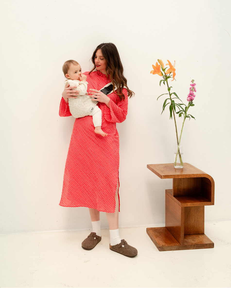 Enfant porté sur la hanche dans un porte-bébé physiologique.