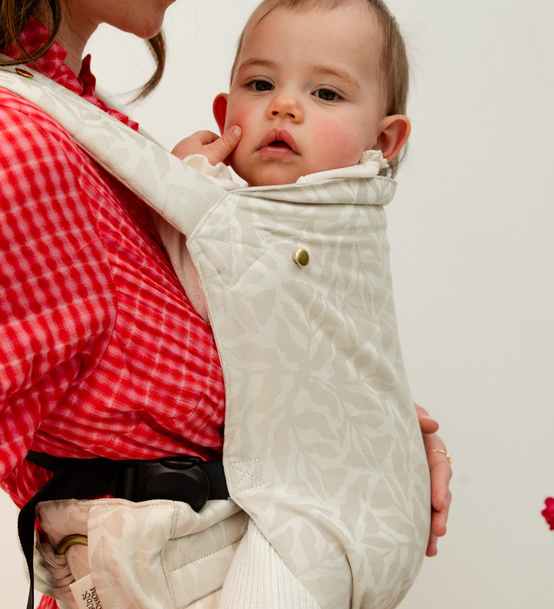 Photo d'une maman portant son bébé en portage physiologique afin de calmer ses pleurs. 
