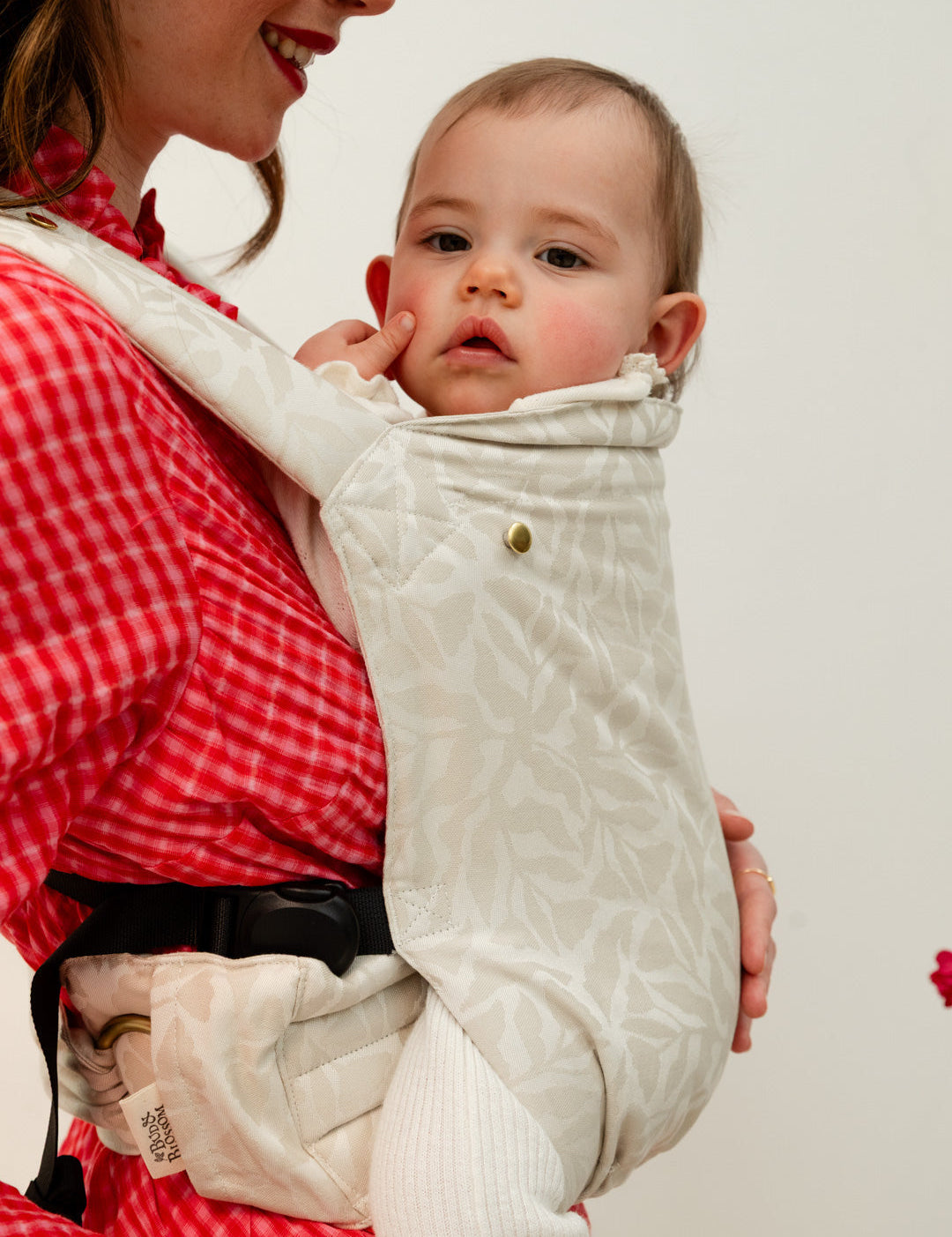 Photo d'une maman portant son bébé en portage physiologique afin de calmer ses pleurs. 