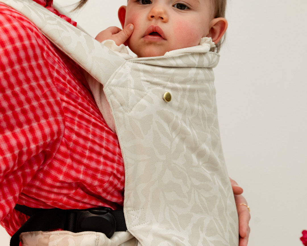 Photo d'une maman portant son bébé en portage physiologique afin de calmer ses pleurs. 
