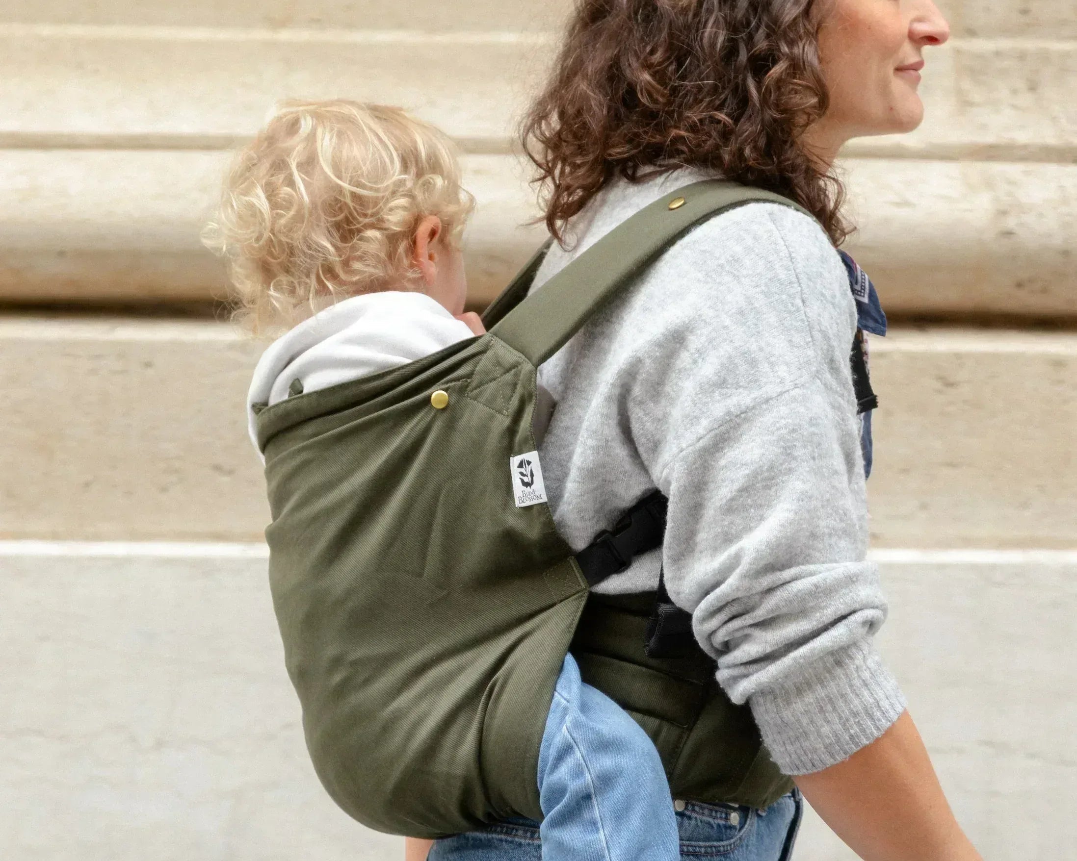 Bambin porté sur le dos dans un porte-bébé physiologique Exquis+ Toddler.
