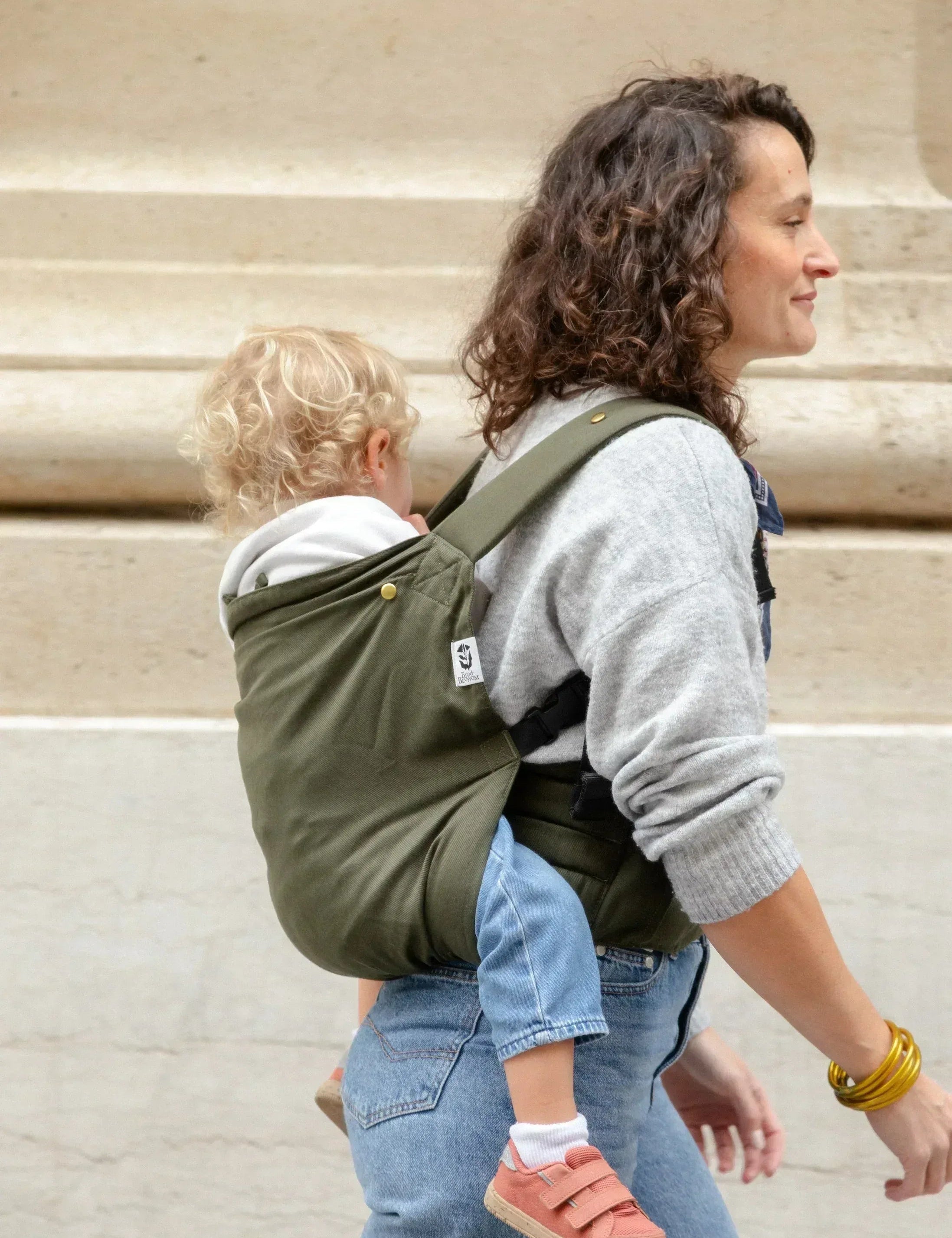 Bambin porté sur le dos dans un porte-bébé physiologique Exquis+ Toddler.