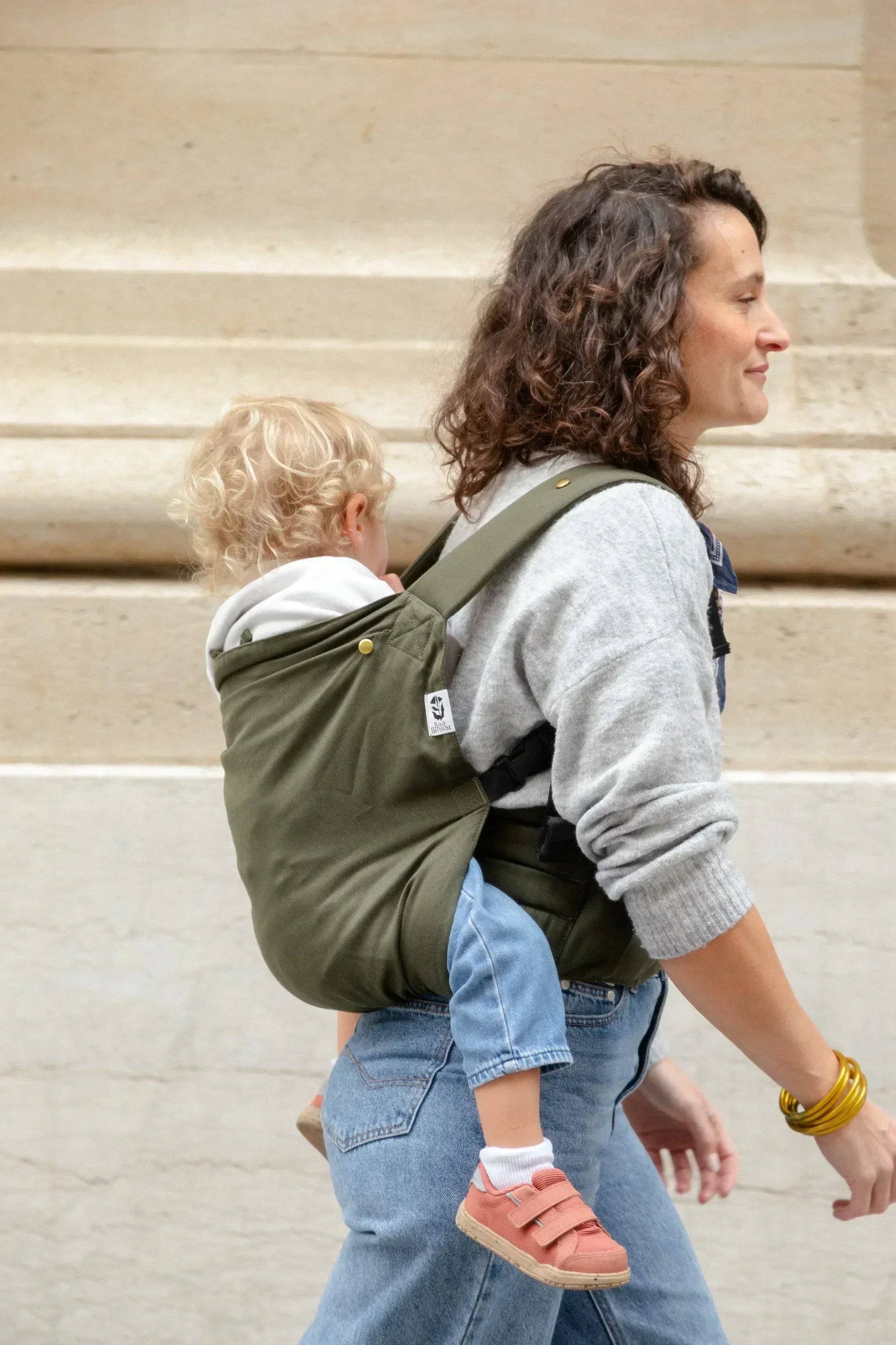 Bambin porté sur le dos dans un porte-bébé physiologique Exquis+ Toddler.