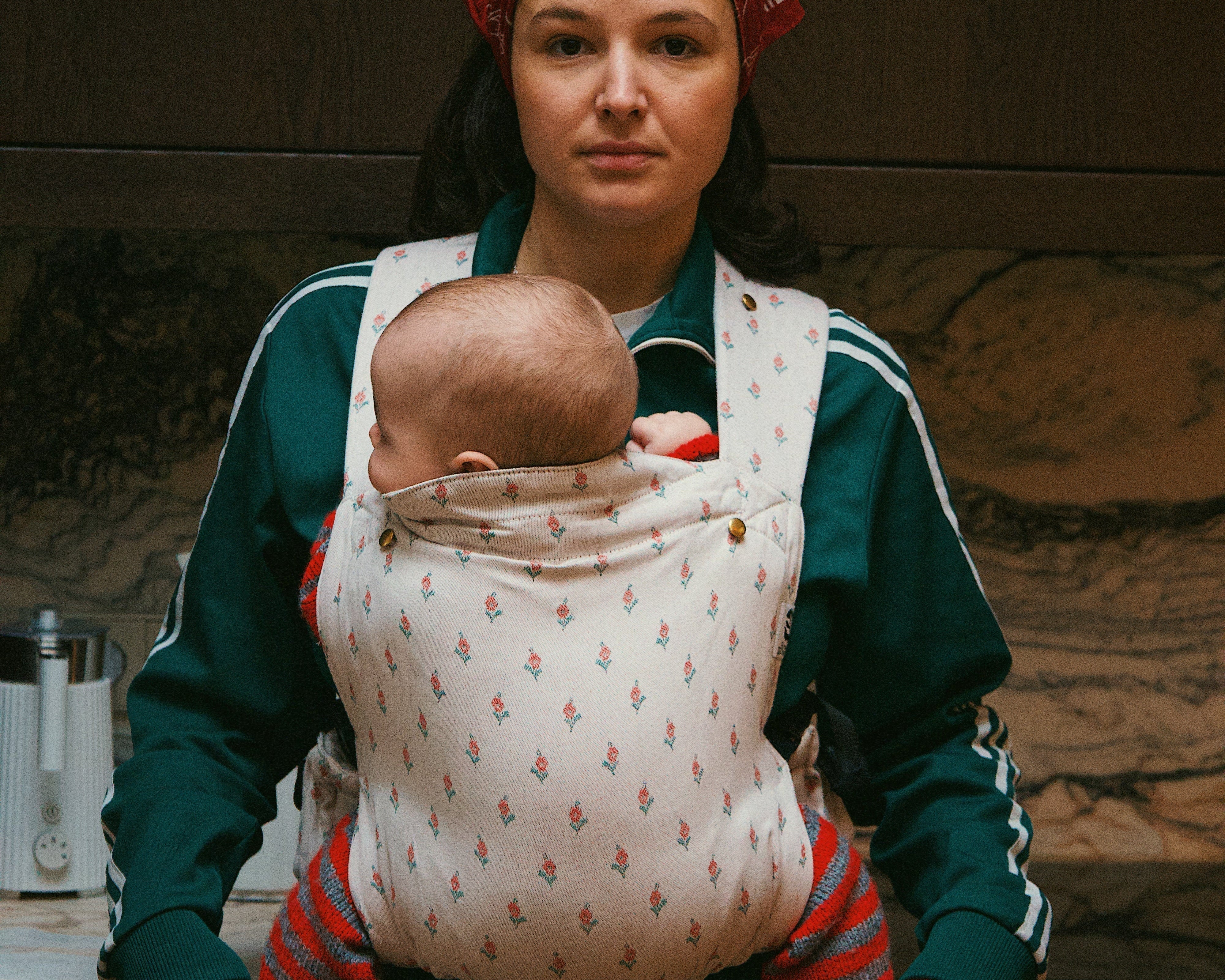 Bébé installé haut et proche du corps dans un porte-bébé physiologique