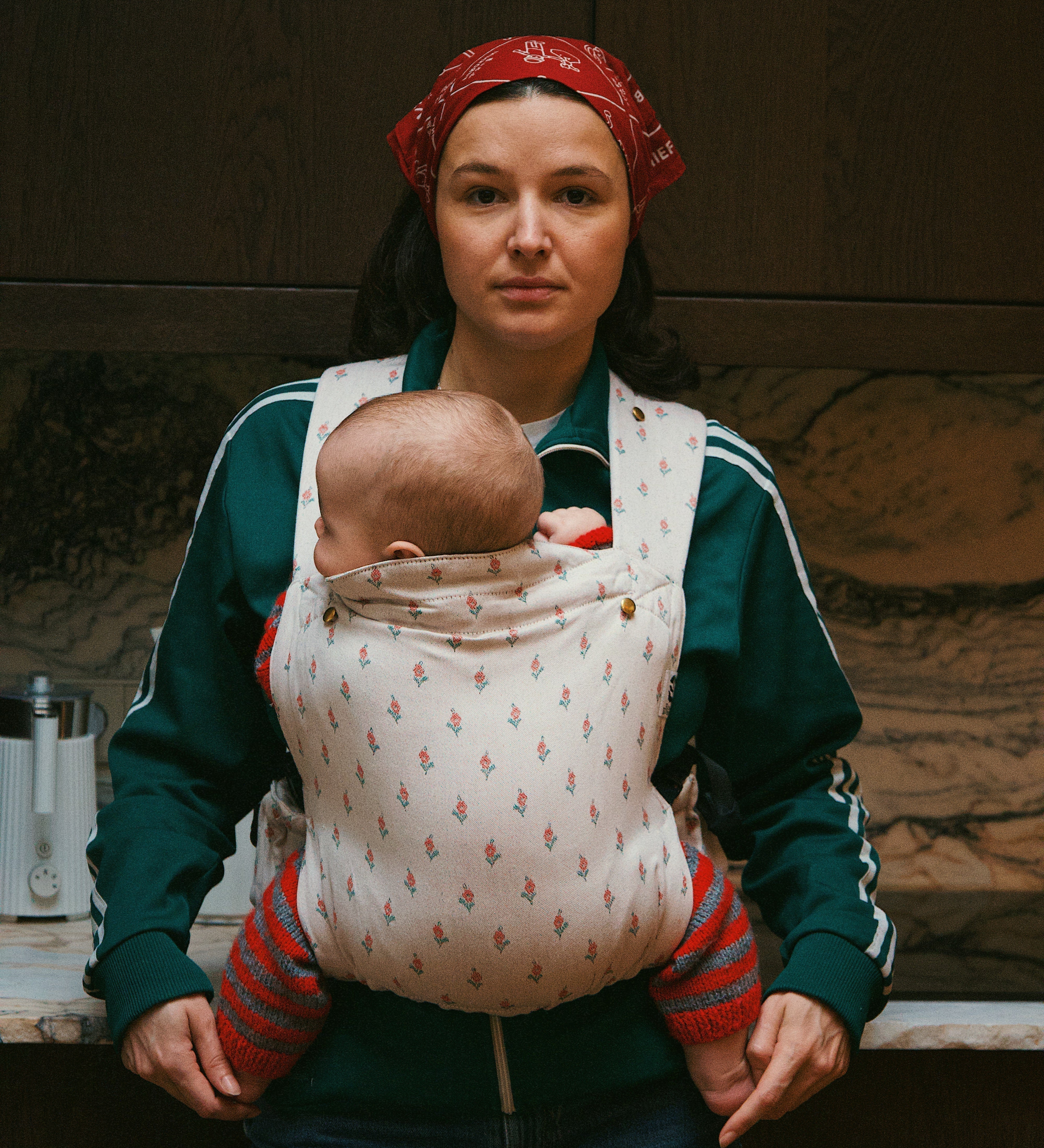 Bébé installé haut et proche du corps dans un porte-bébé physiologique