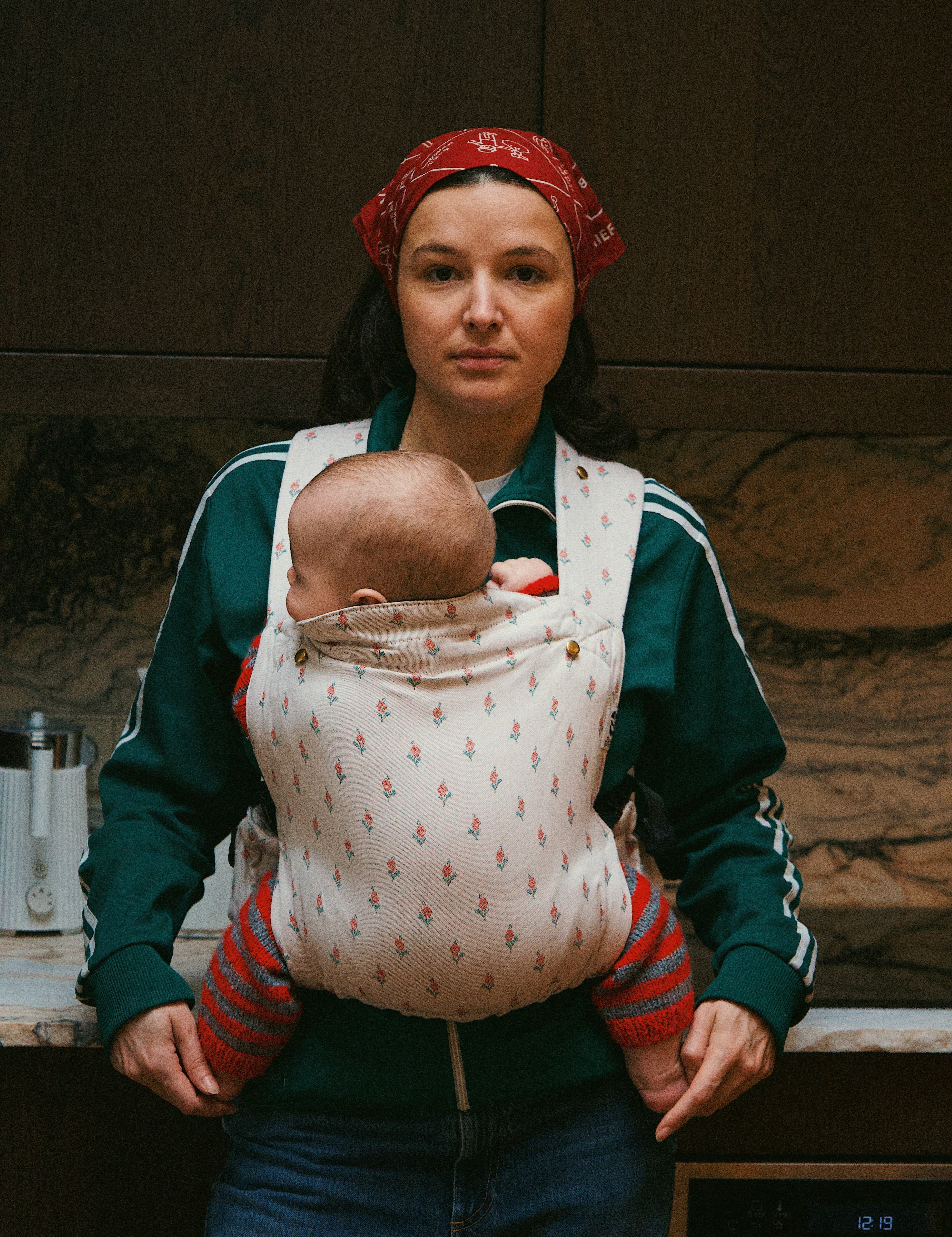 Bébé installé haut et proche du corps dans un porte-bébé physiologique