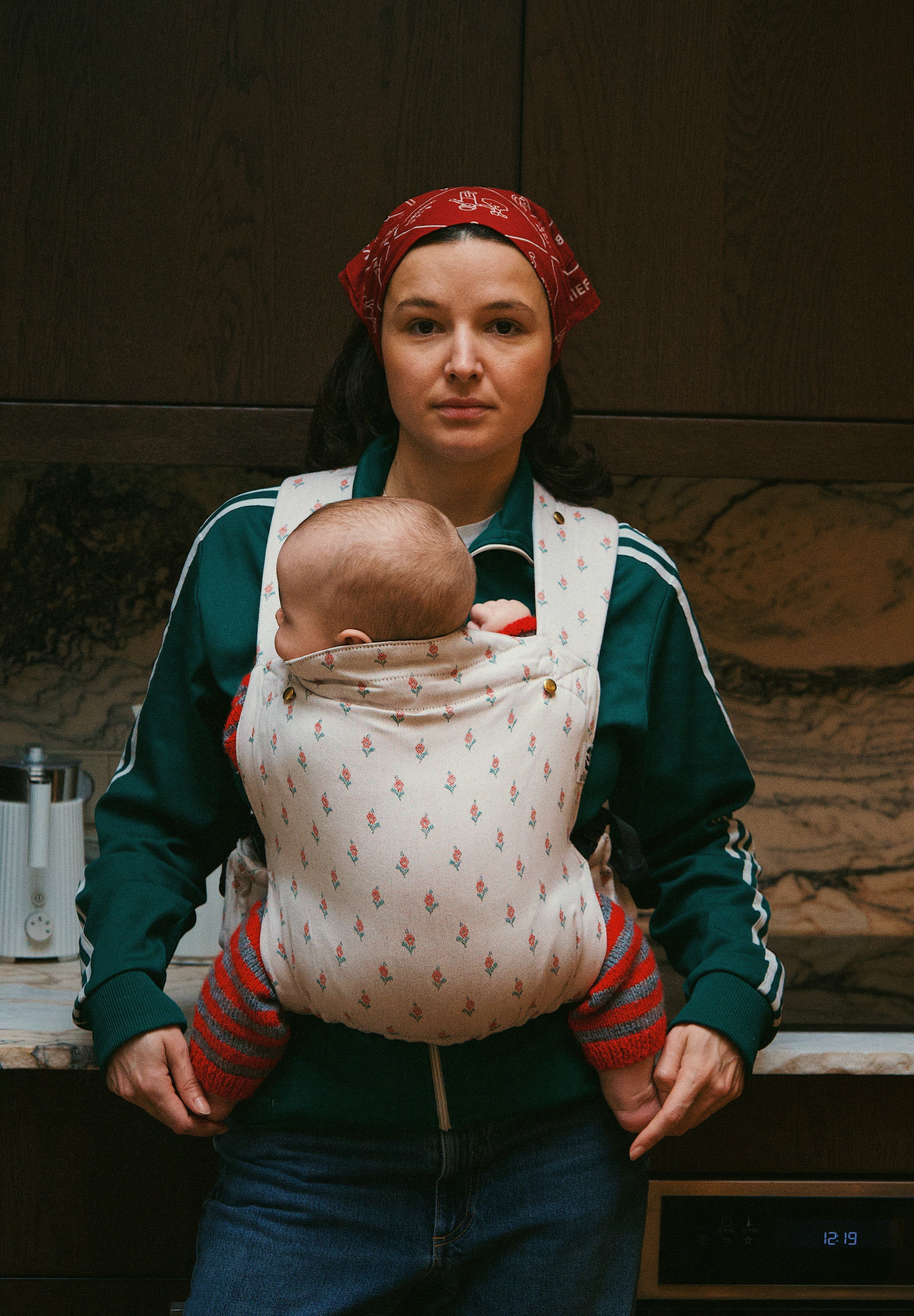 Bébé installé haut et proche du corps dans un porte-bébé physiologique