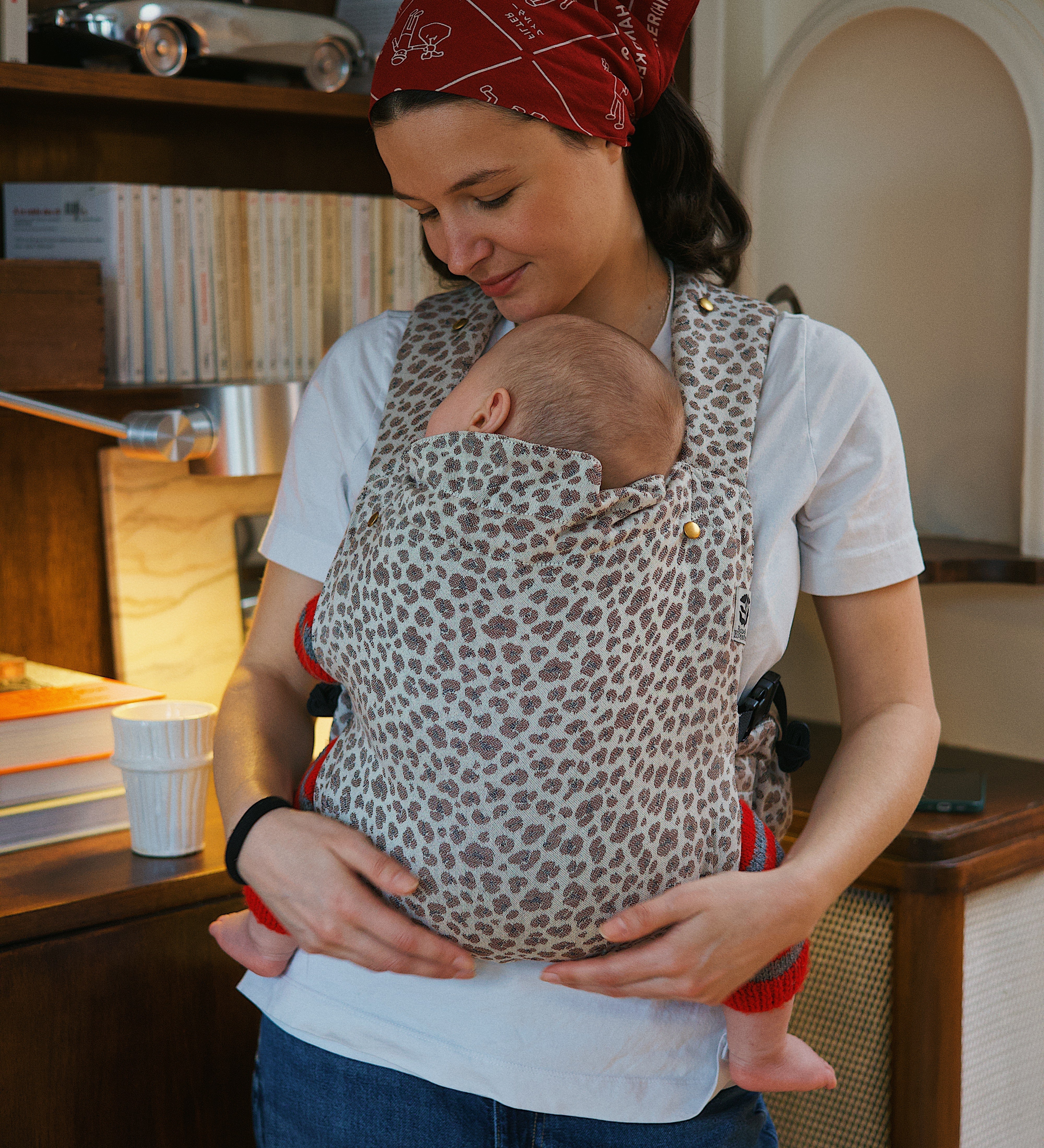 Maman portant son bébé en position ventrale dans un porte-bébé physiologique Bud & Blossom.