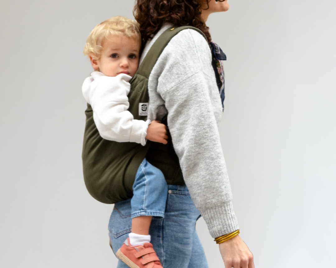 Enfant de 3 ans porté en porte-bébé Exquis+ Toddler sur le chemin de l’école