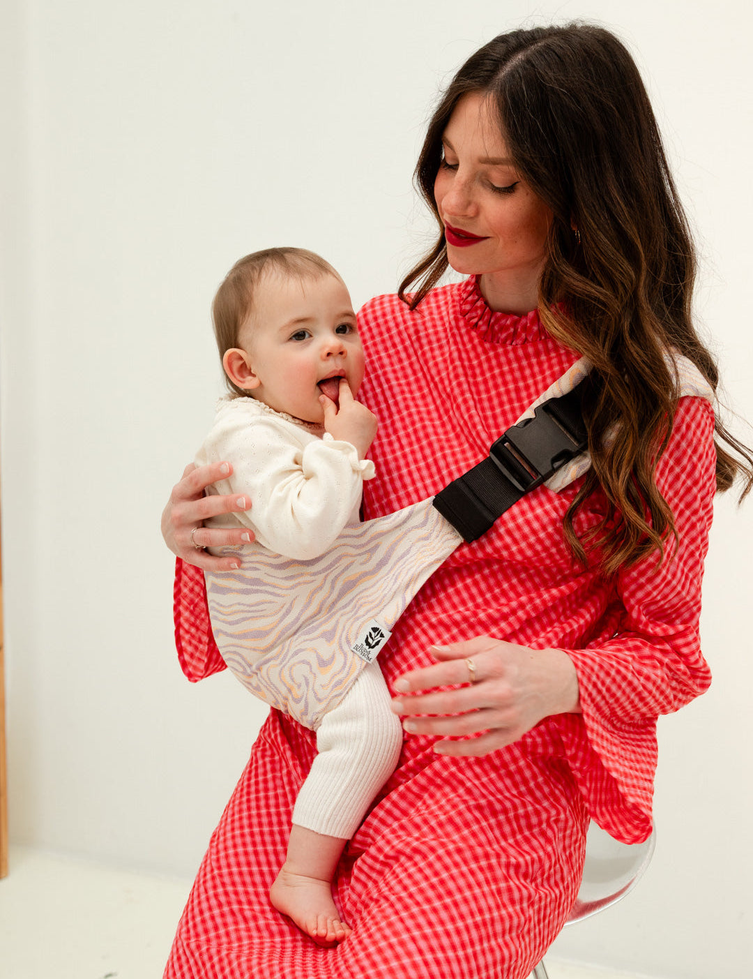 Parent portant son bébé sur la hanche avec le porte-bébé Swing.