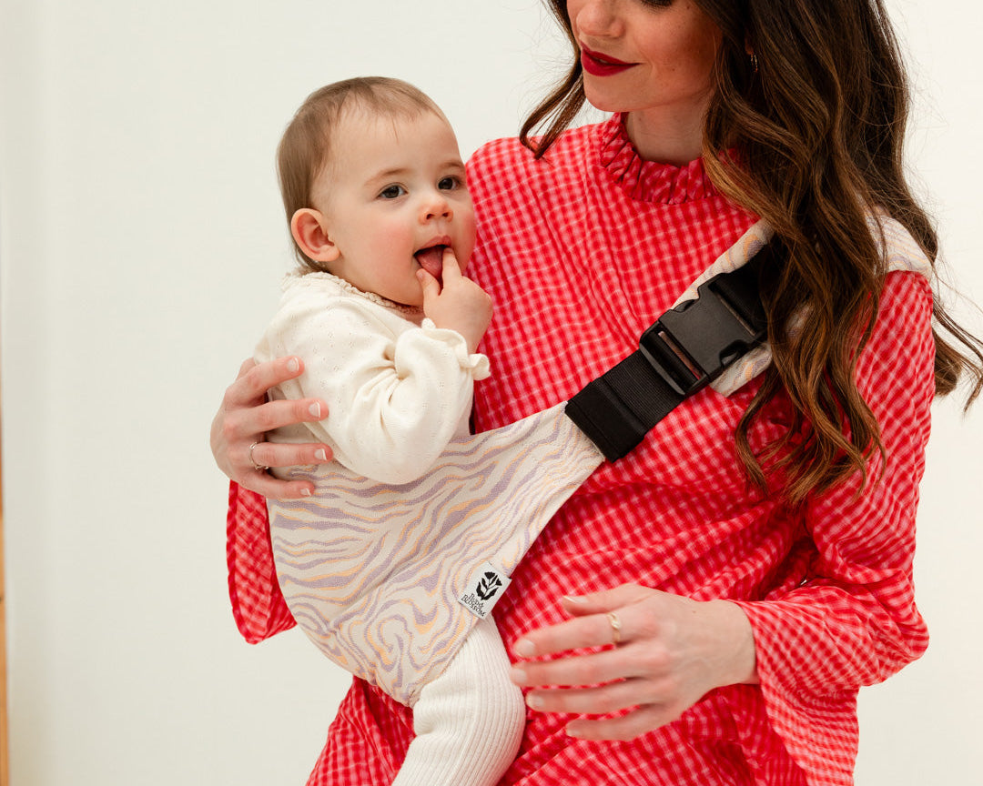 Parent portant son bébé sur la hanche avec le porte-bébé Swing.