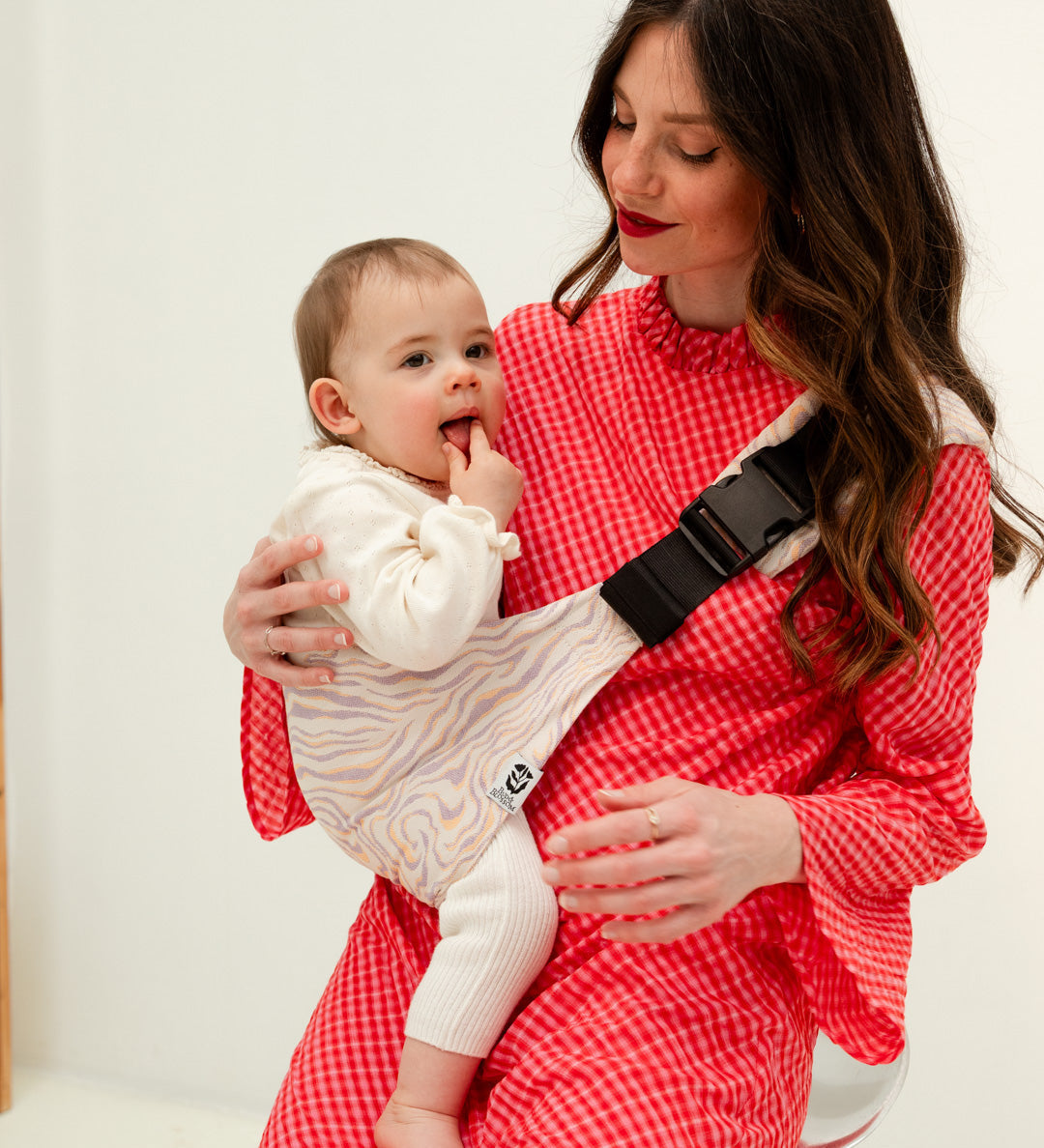 Parent portant son bébé sur la hanche avec le porte-bébé Swing.