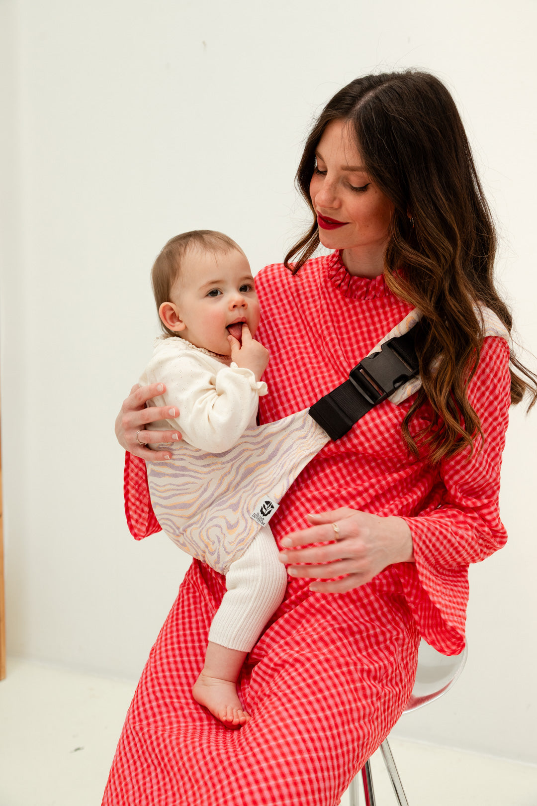 Parent portant son bébé sur la hanche avec le porte-bébé Swing.