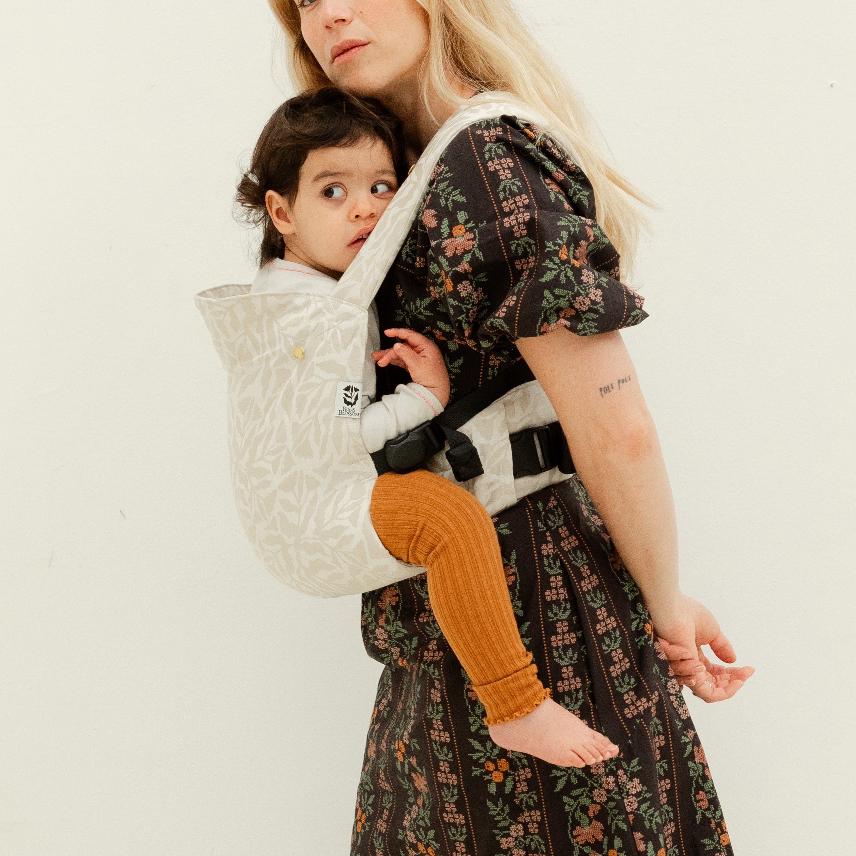 Maman utilisant le porte-bébé fleuri physiologique Exquis avec son bambin de 2 ans