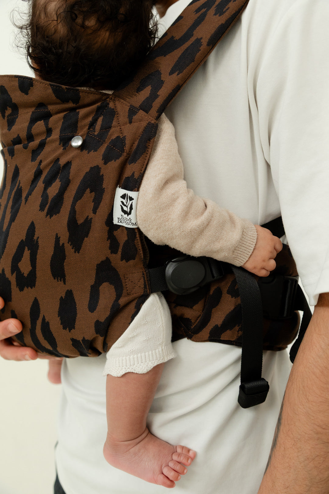 Porte-bébé physiologique Exquis Wild porté par un jeune papa